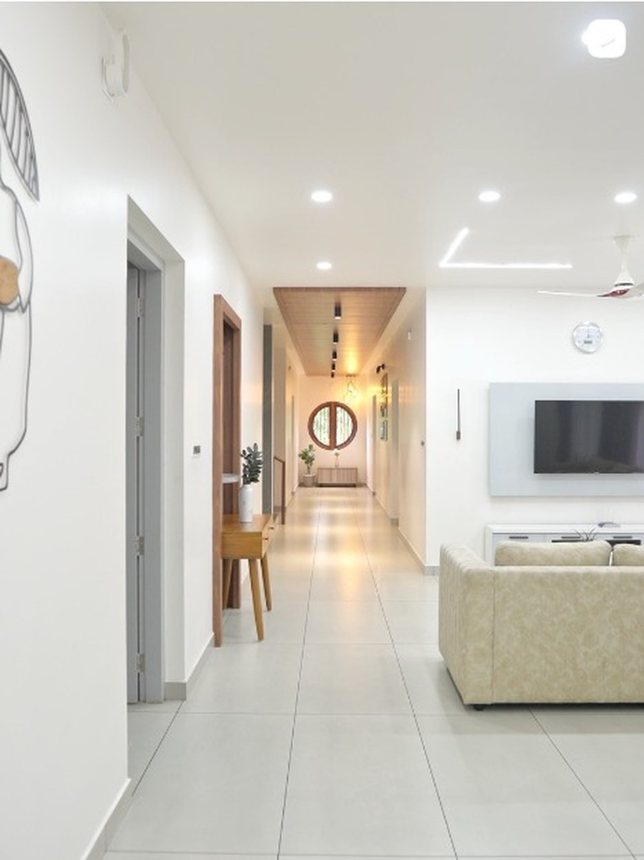 Bright white D'Casa Homes corridor with recessed lighting, wooden doors and large-format floor tiles