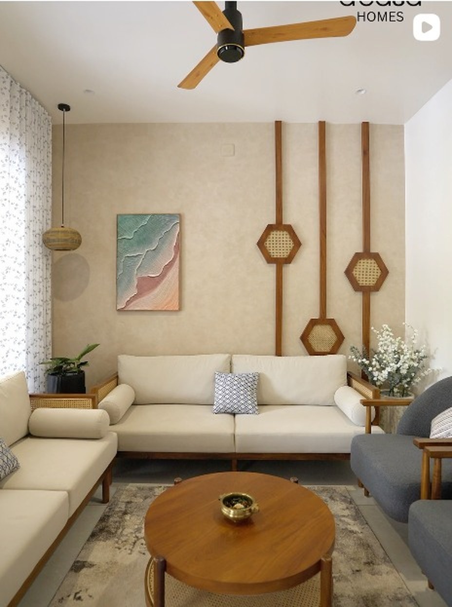 Living room with cream upholstered sofas, teak wall detailing and a round wooden coffee table