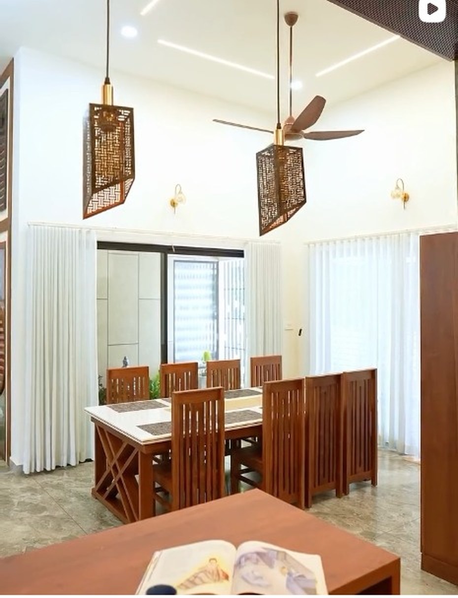 Bright dining space with a teak dining set, sheer curtains and rattan pendant lights