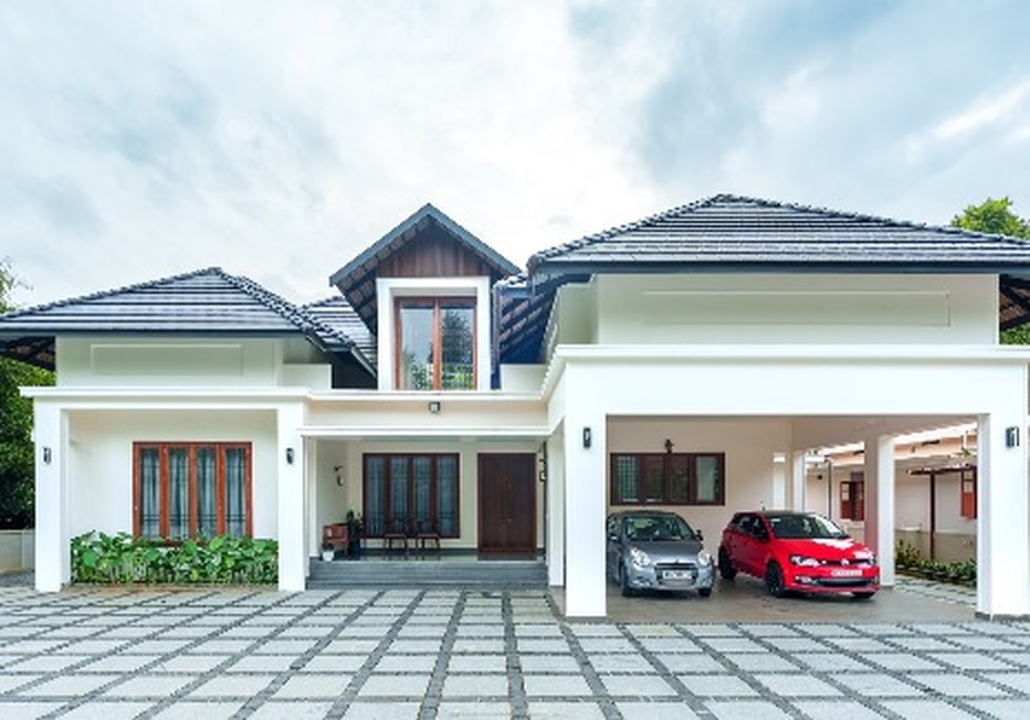 Symmetrical white home with dark tiled gable roofs, red doors and a wide paved forecourt